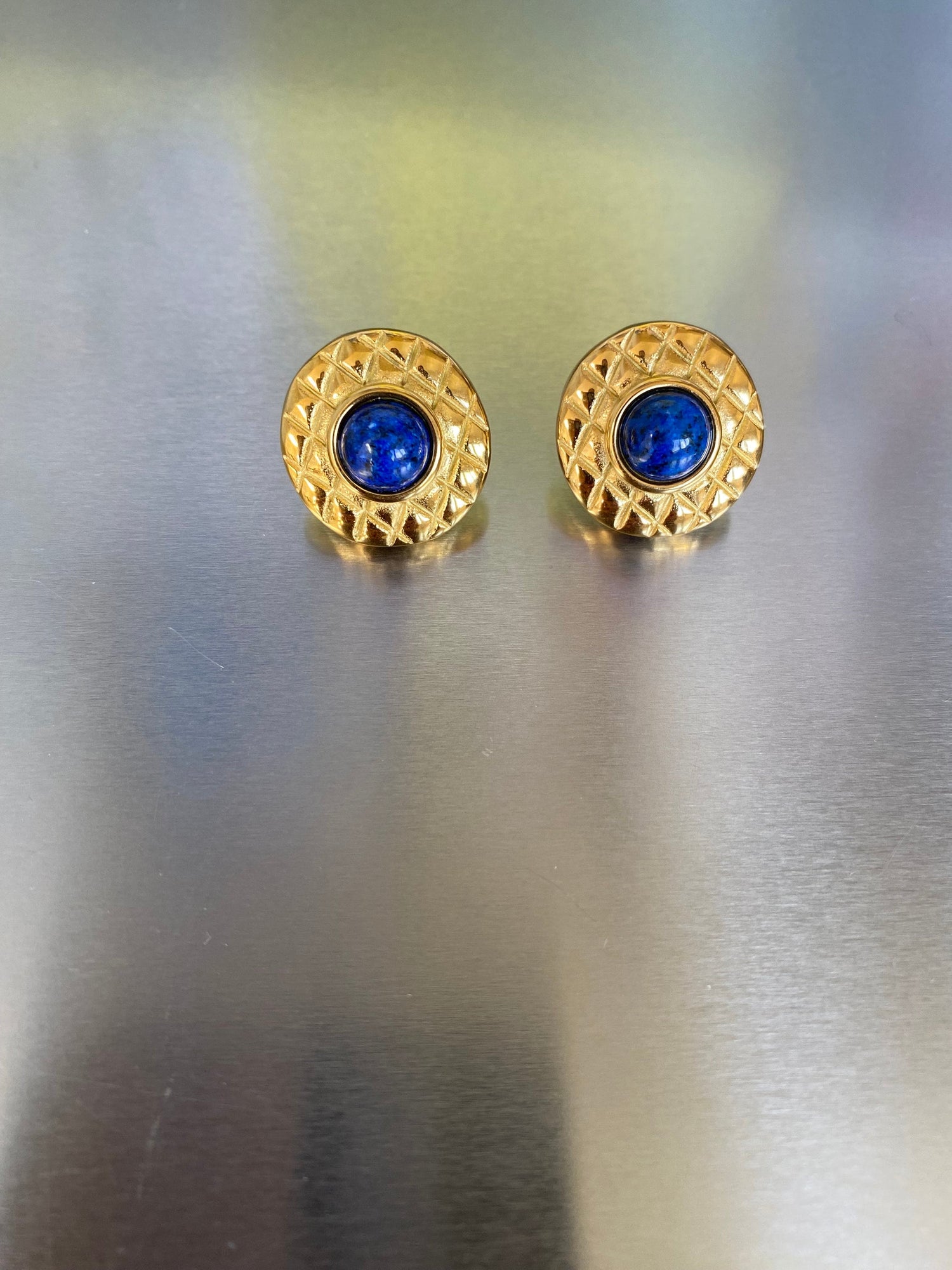 Textured gold dome earrings with striking cobalt blue center detail.
