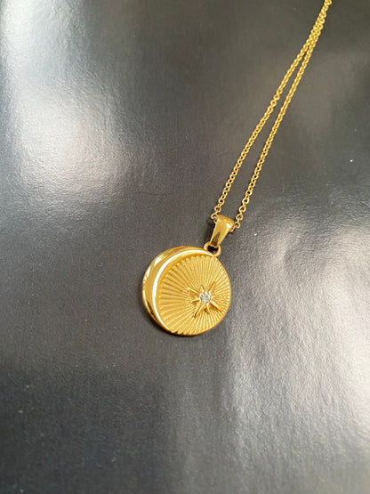 Minimalist gold coin pendant necklace with zircon displayed flat on a black surface